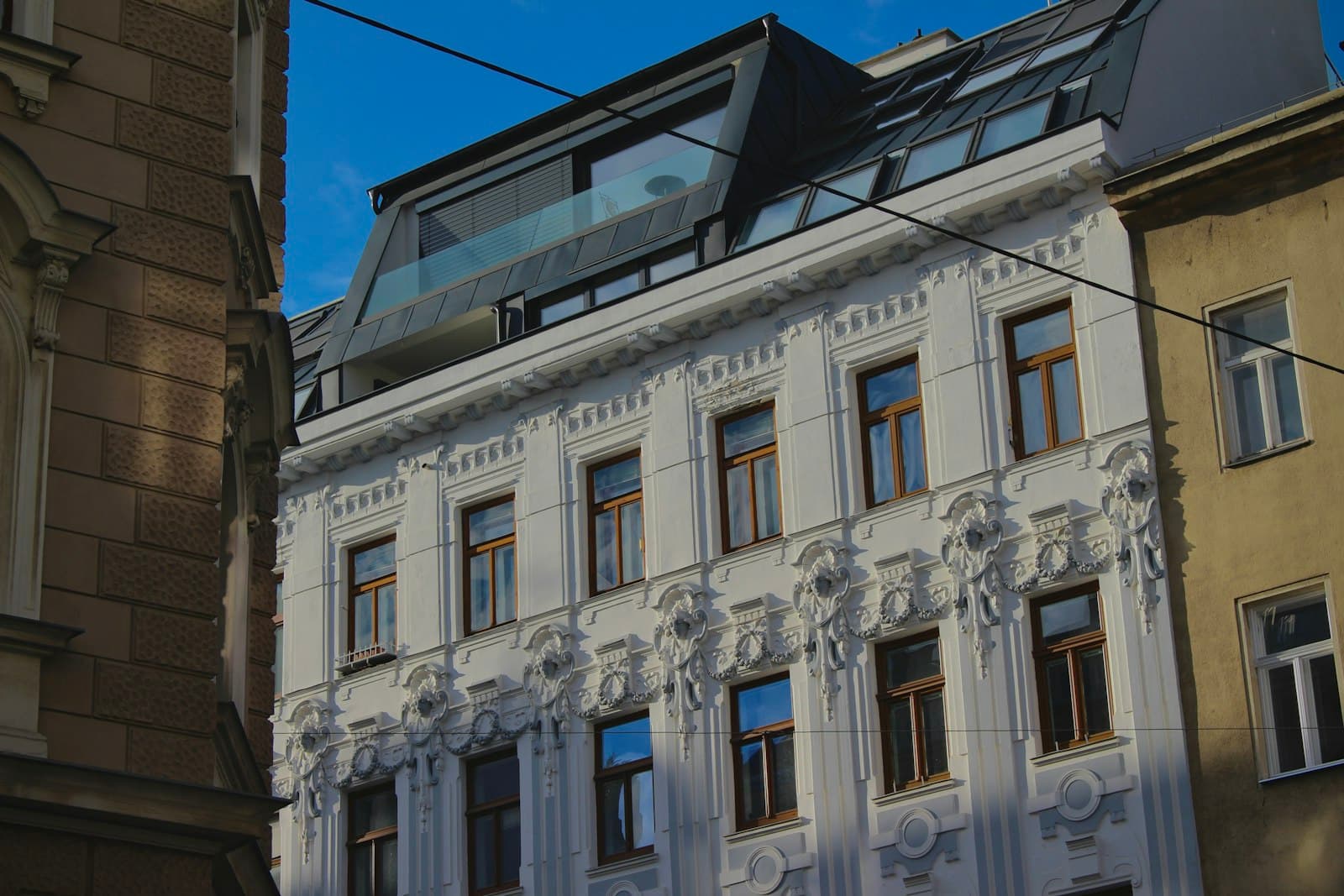 Sanierte Gründerzeitfassade mit Stuckornamenten, Holzfenstern und ausgebautem Dachgeschoss neben unsanierten Altbauten, Foto